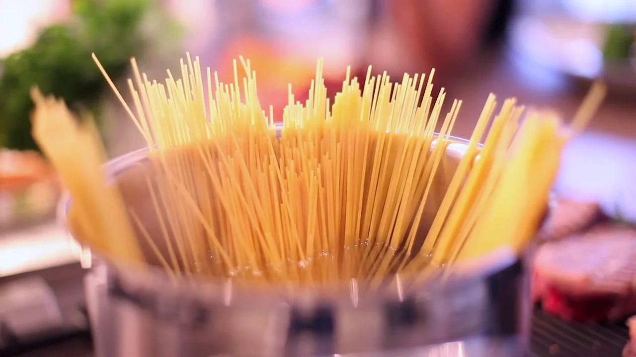 Spaghetti fächern sich in einem Topf mit kochendem Wasser auf