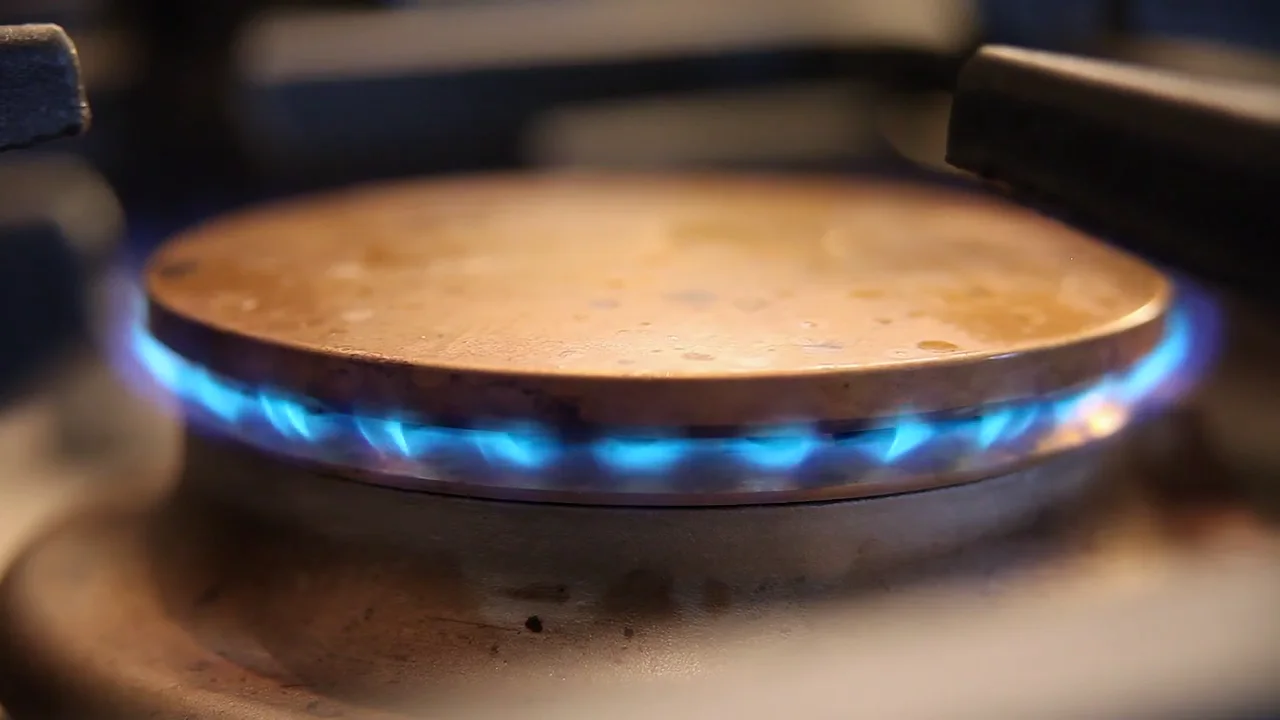 Pfanne auf dem blauen Flammenkranz eines Gaskochfelds