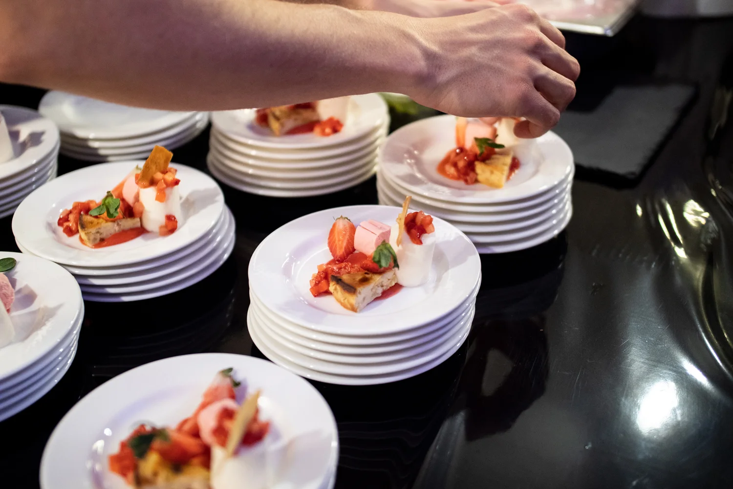 Desserts mit Erdbeeren werden auf einer dunklen Arbeitsfläche angerichtet